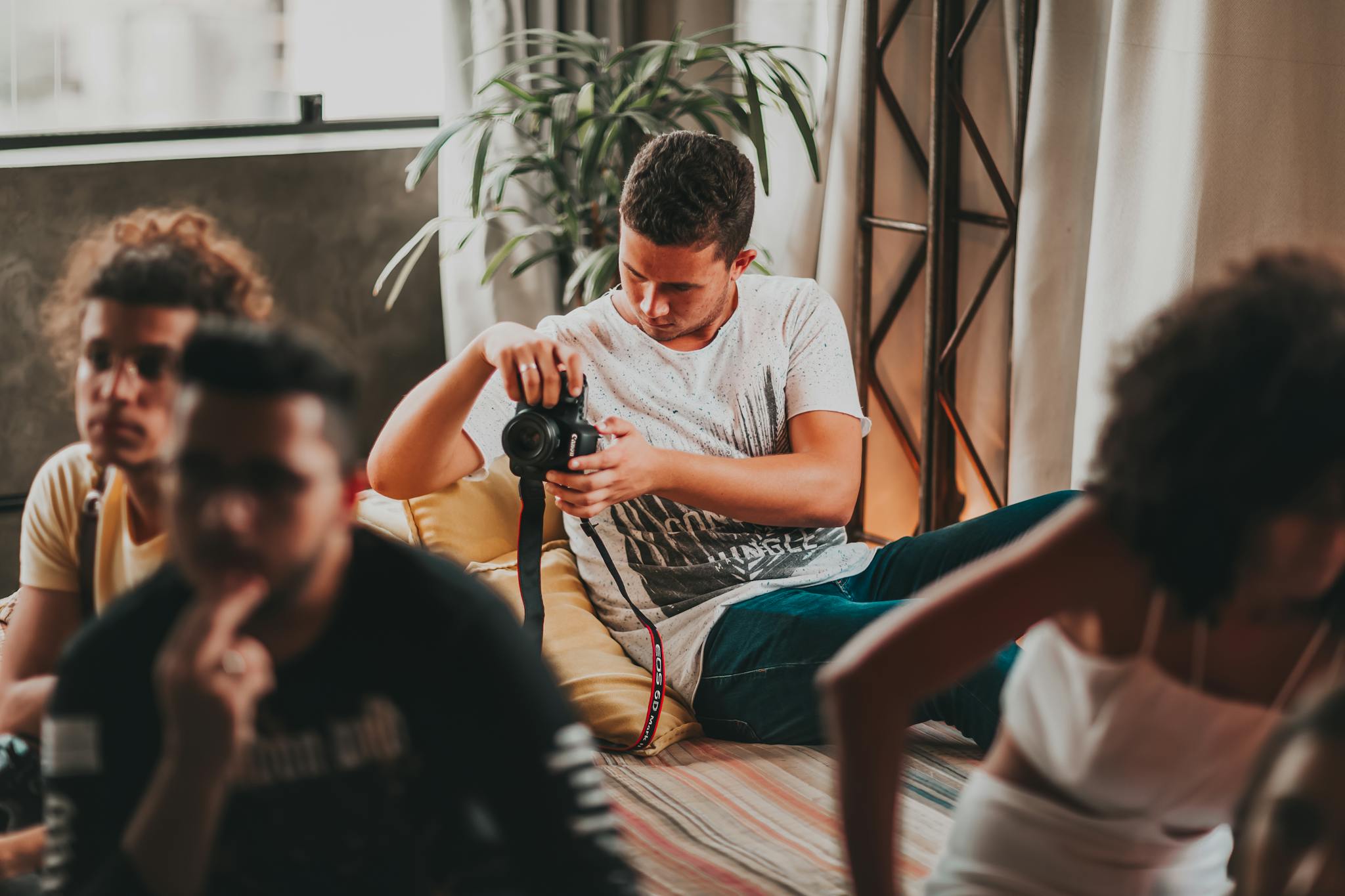 Concentrated young man taking photos on professional camera during work in modern studio